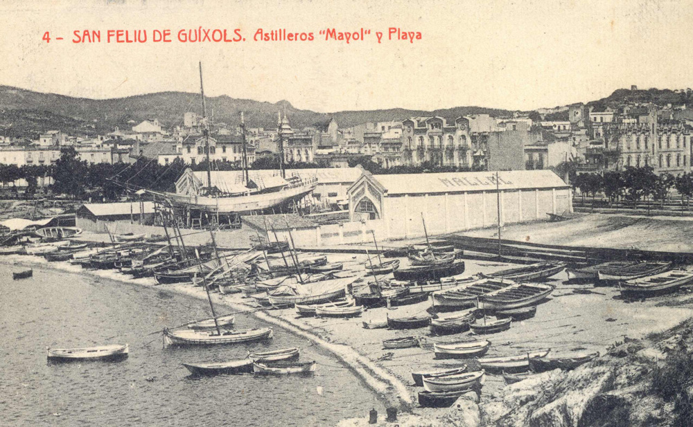 Les drassanes Mallol al racó de Llevant de la platja de Sant Feliu amb el veler Sant Jordi en construcció (1918 – 1921). AMSFG. Fons Ajuntament de Sant Feliu de Guíxols. Autor: Desconegut.