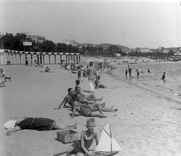 Casetes de banys al racó de garbí amb diversos banyistes a la sorra (1922 – 1930). AMSFG. Fons Francesc Llorens. Autor: Francesc Llorens.