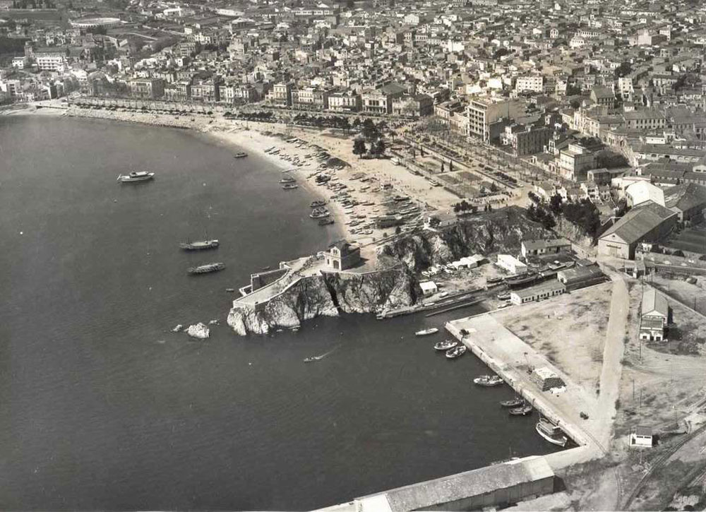 Vista aèria del passeig i la platja amb la punta dels Guíxols en primer terme, 1965 AMSFG. Col·lecció Municipal d’Imatges (Autor: Paisajes Españoles Fotografías Aéreas).